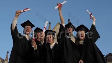 <strong>终于</strong>自由了。 一群穿着毕业礼服、戴着硕士帽的学生站在一起，举着他们的名字